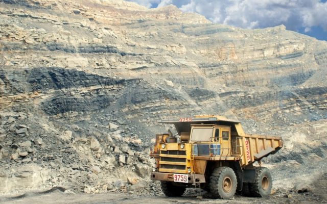 A yellow haul truck marked 9759 on a gravel road in an open-pit mine