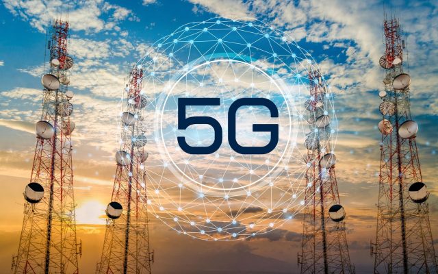 Telecommunications towers against a cloudy sunset sky with a 5G data graphic overlay