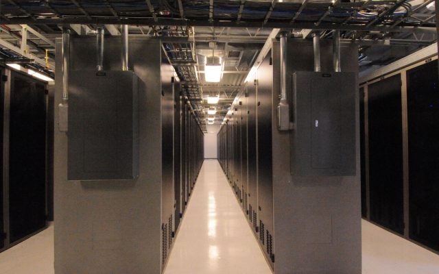 Rows of server racks in a data centre aisle with overhead cable trays
