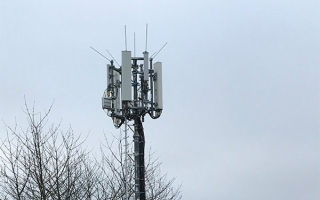Communications tower with rectangular antennas against a grey sky