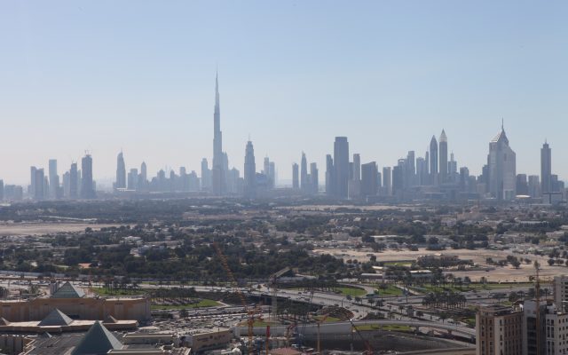Hazy Dubai skyline with the Burj Khalifa and high-rise towers, construction cranes in the foreground